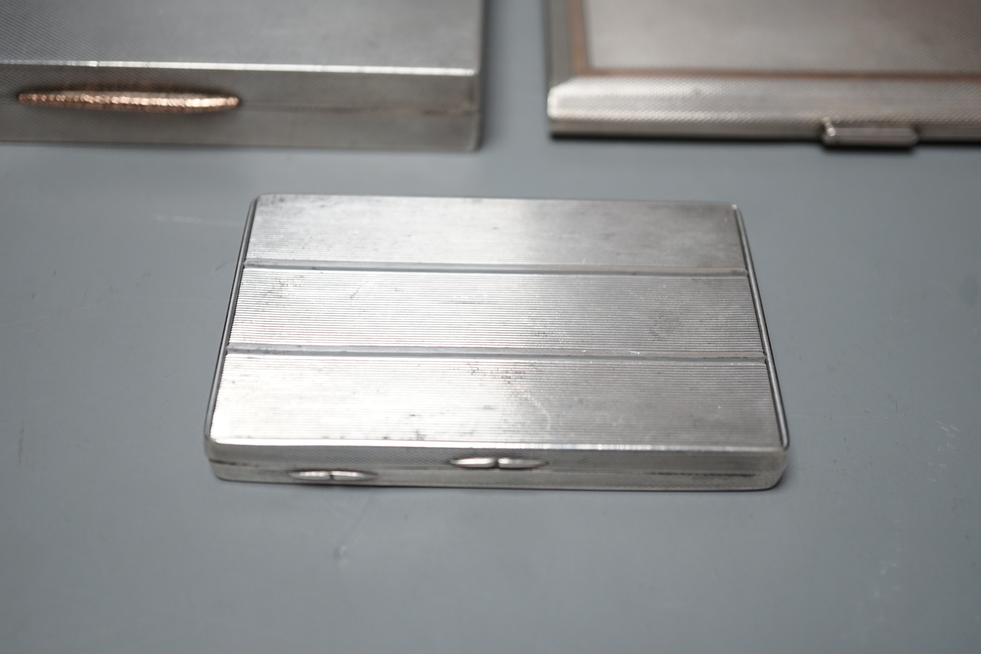A George VI engine turned silver rectangular cigarette box/case, engraved with a squirrel, W.H. Manton Ltd, Birmingham, 1942, 12.2cm, one other Mappin & Webb silver cigarette case and a continental white metal snuff box.